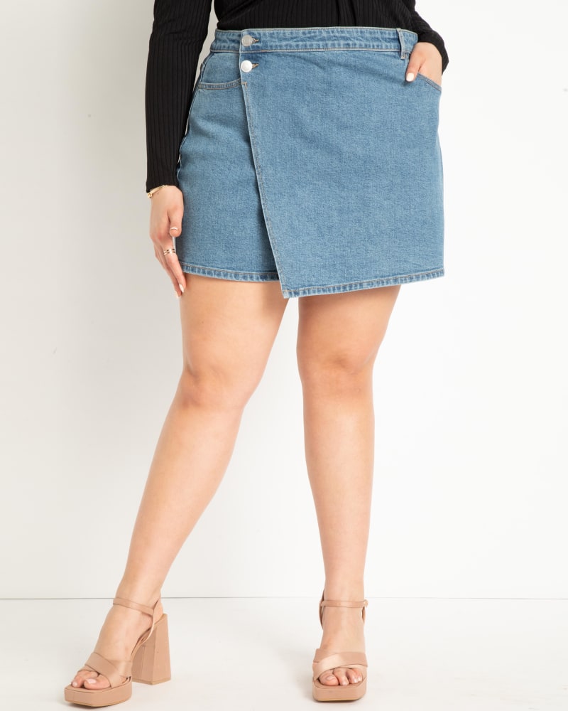 Front of a model wearing a size 28 Denim Skort in Medium Wash by ELOQUII. | dia_product_style_image_id:284471